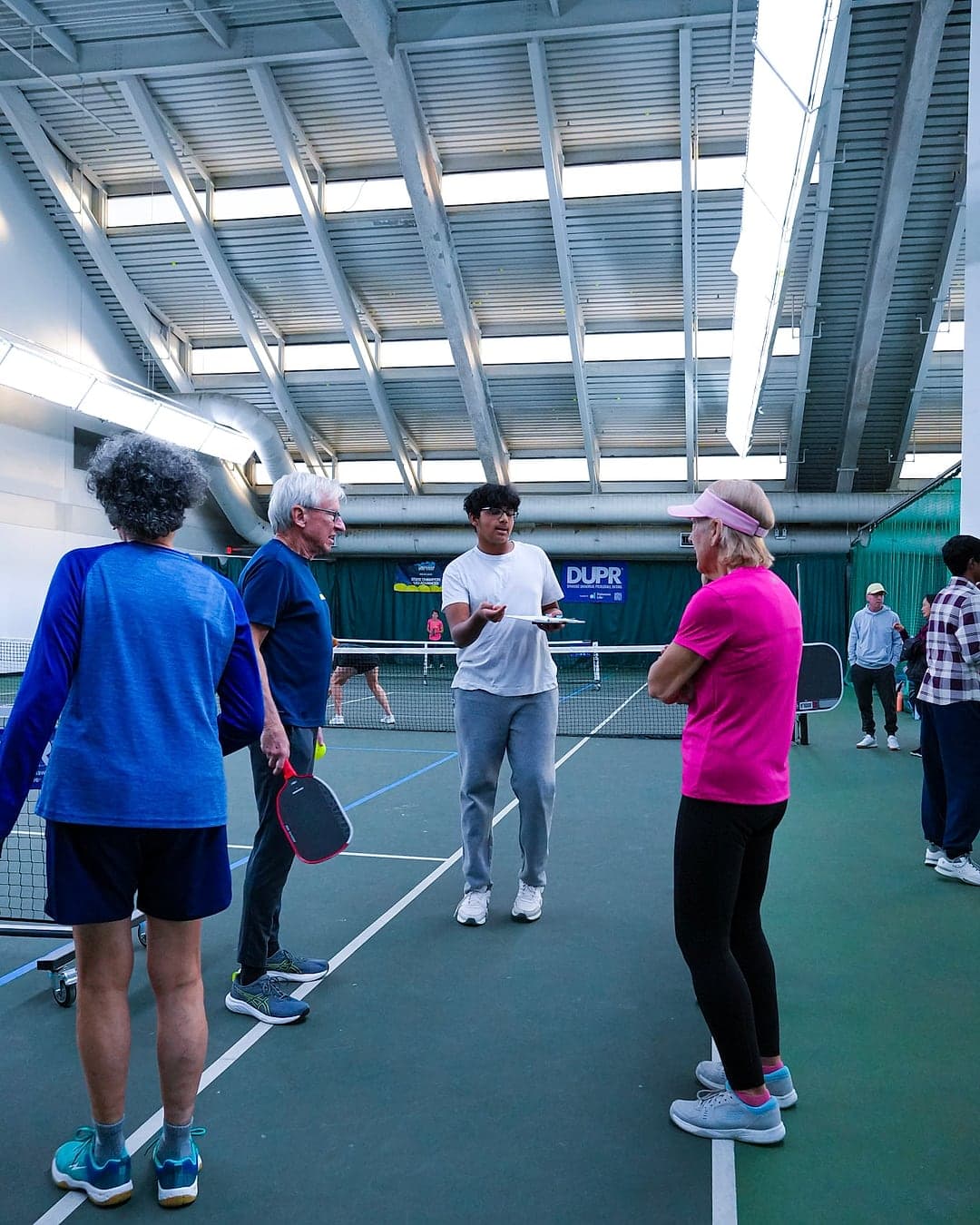 A student organizer with the clipboard, briefing players at the net